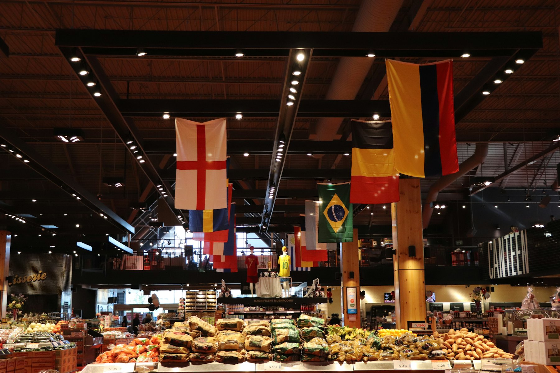 A busy market hall seen from above with produce stalls and hanging flags
